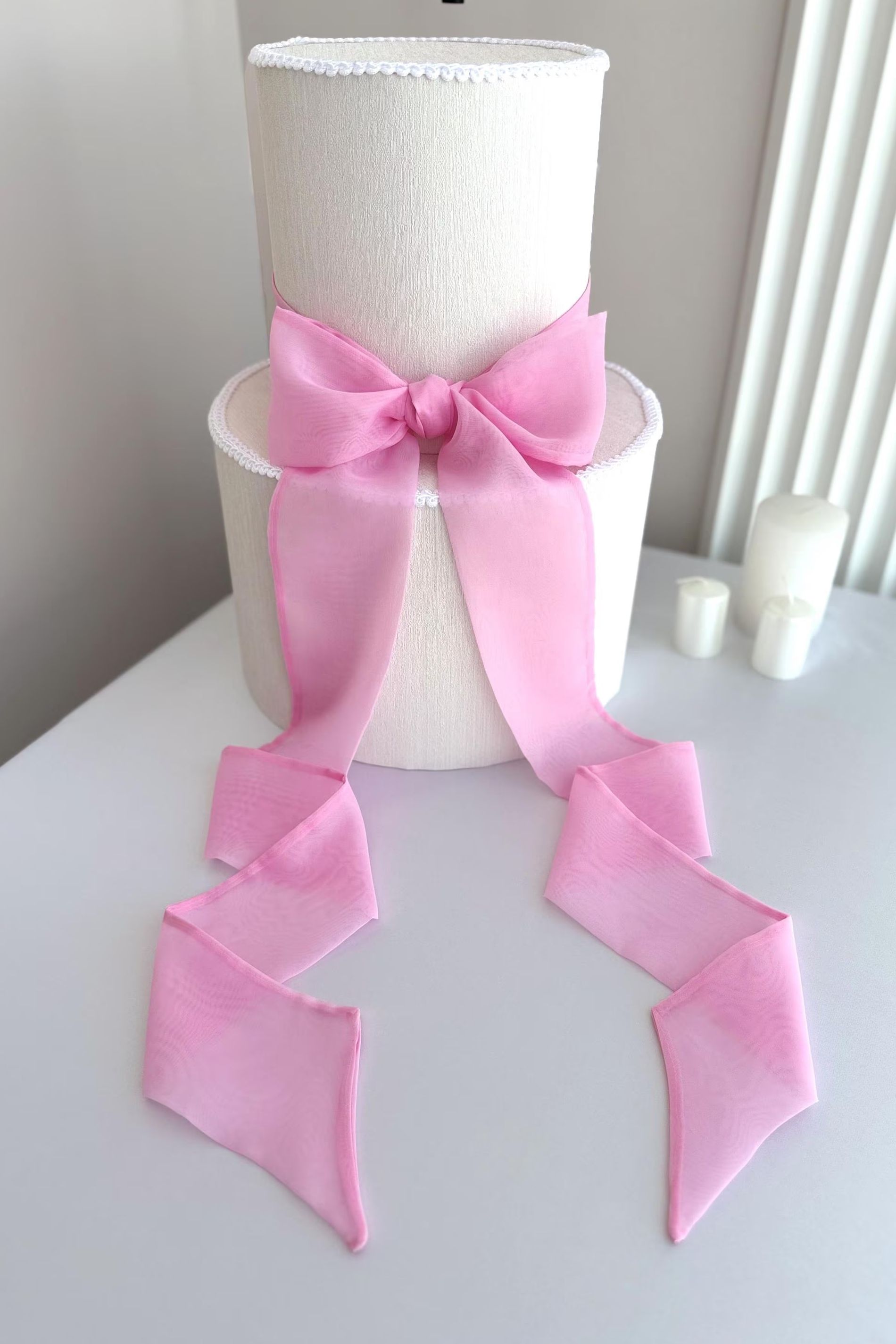 White cake with a large pink bow on a white surface