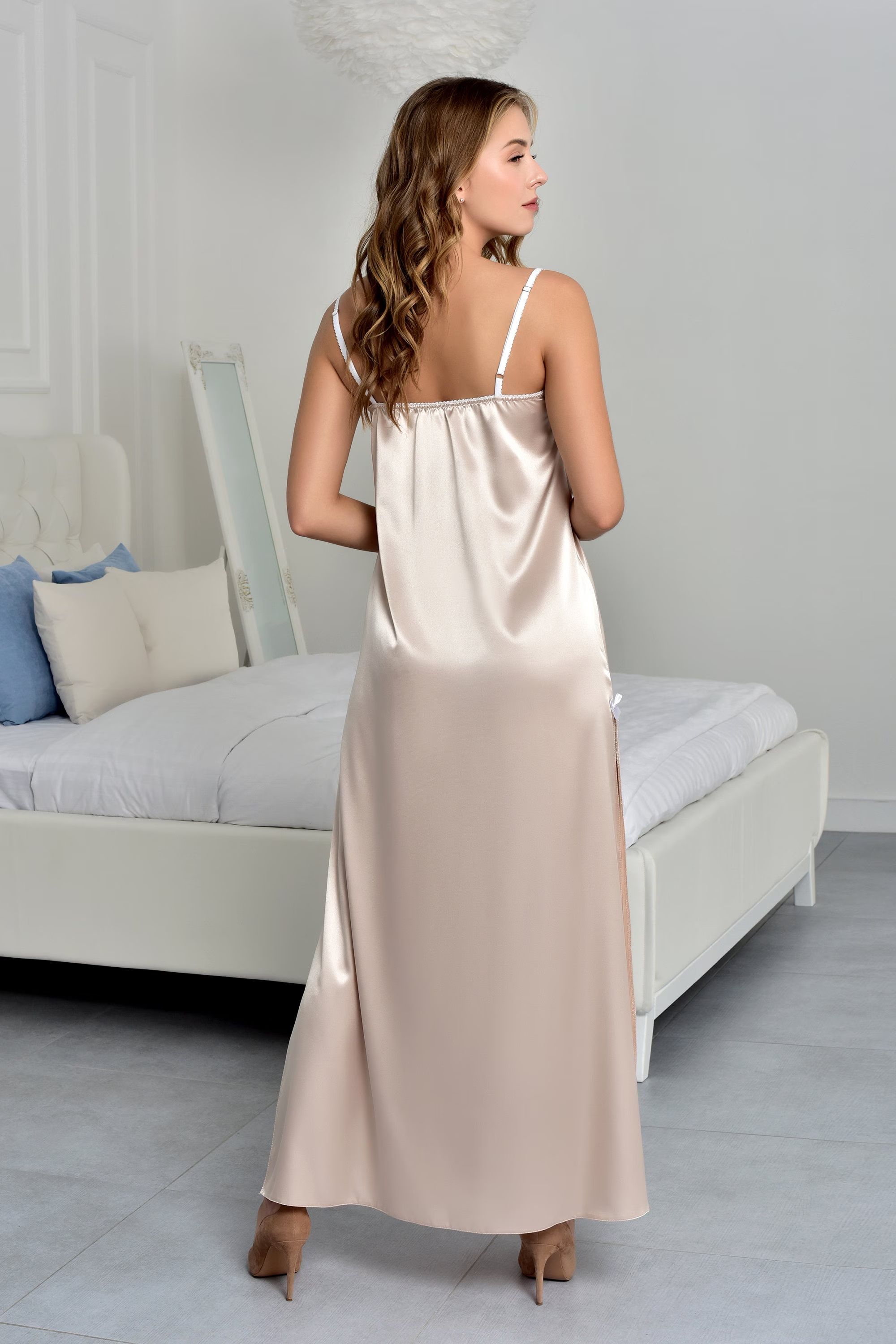 Woman wearing a long beige satin nightgown in a bedroom setting.