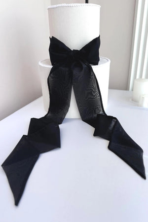 White lampshade with a large black bow on a white surface