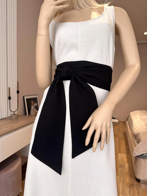 A mannequin wearing a white dress with a pink linen sash tied in the middle.