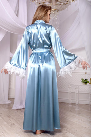 Woman wearing a light blue satin robe with white fringes in a elegant room.