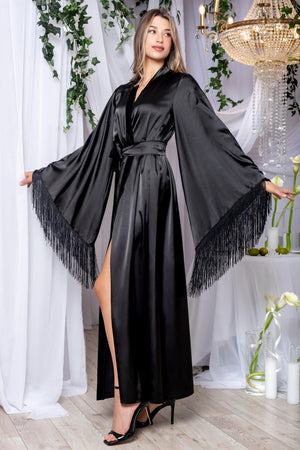 Woman wearing a black satin robe with fringe details in an elegant indoor setting.