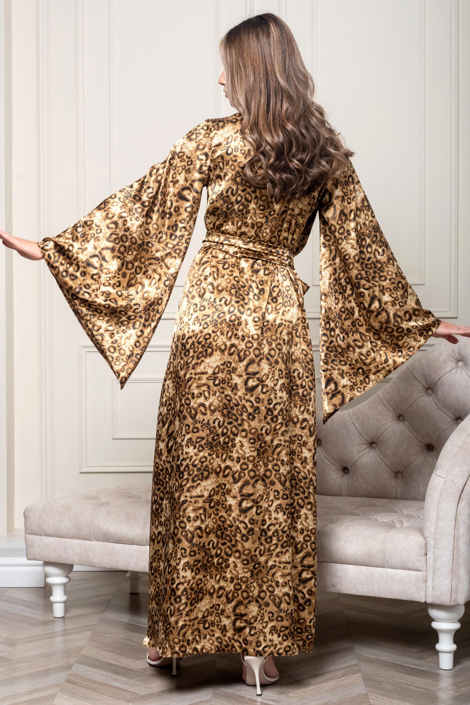 Woman in a leopard print dress standing in a room with a gray sofa.