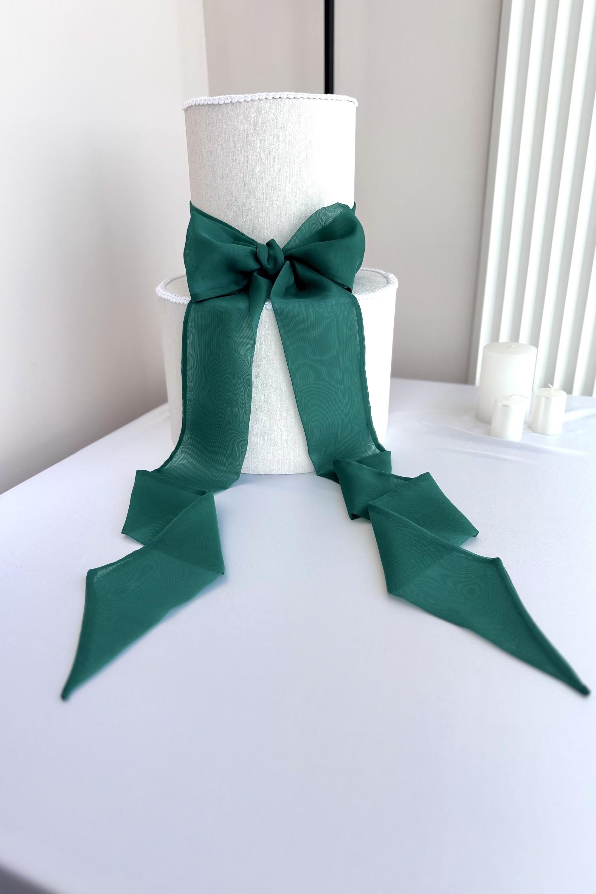 White lampshade with a large green bow on a white surface