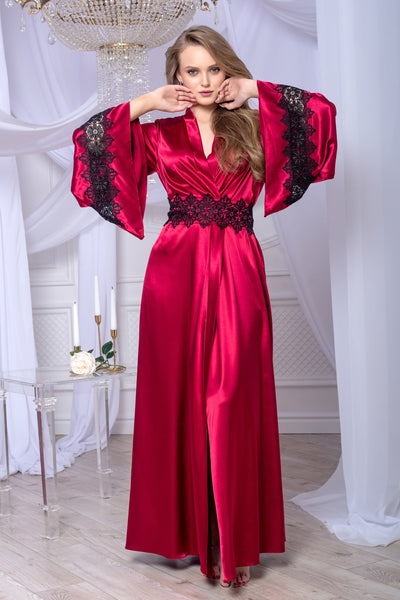 Woman wearing a red evening gown with black lace details in an elegant indoor setting.