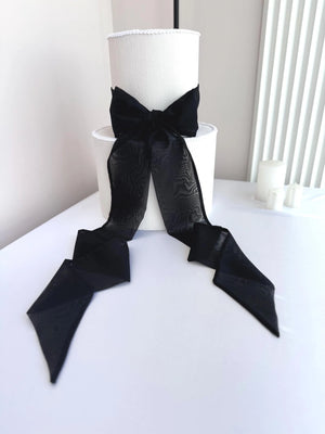 White lampshade with a large black bow on a white surface