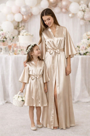 Junior flower girl wearing champagne beige satin robe at wedding