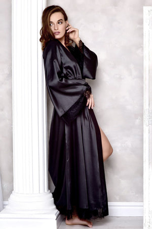 Woman wearing a black satin robe against a white wall