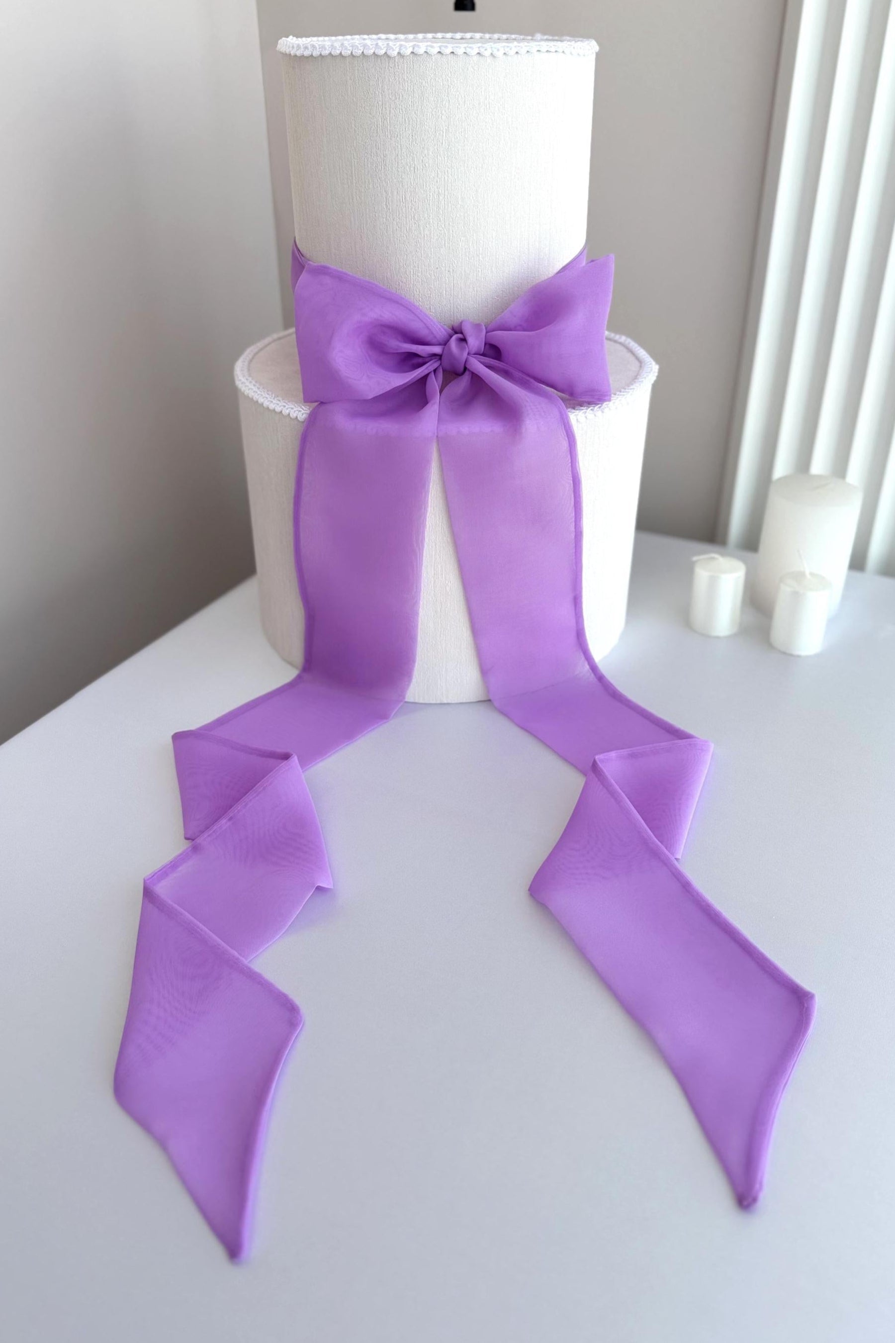 White cake with a large purple bow on a white surface