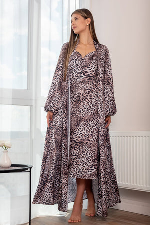 A woman sitting in a chair wearing a leopard print nightgown and robe set with wide belt and puff sleeves.