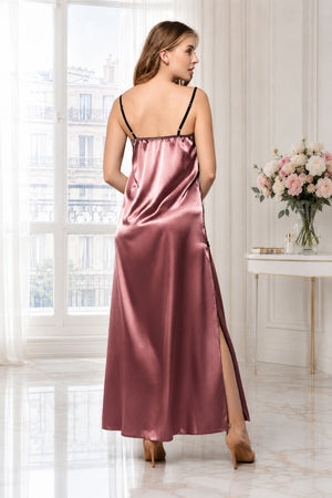 A woman wearing a satin slip dress with a high slit, shown from the back in a bright, elegant room with large windows and a floral side table.