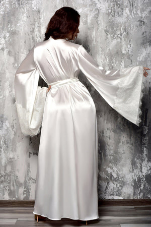 Person wearing a satin robe against a textured gray wall.