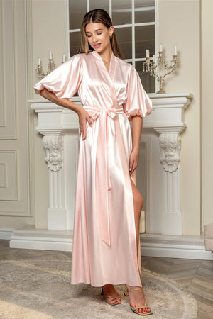 Woman wearing a pink satin robe in an elegant room with a fireplace