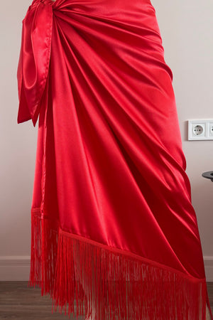 Red satin fabric with fringe on a plain background