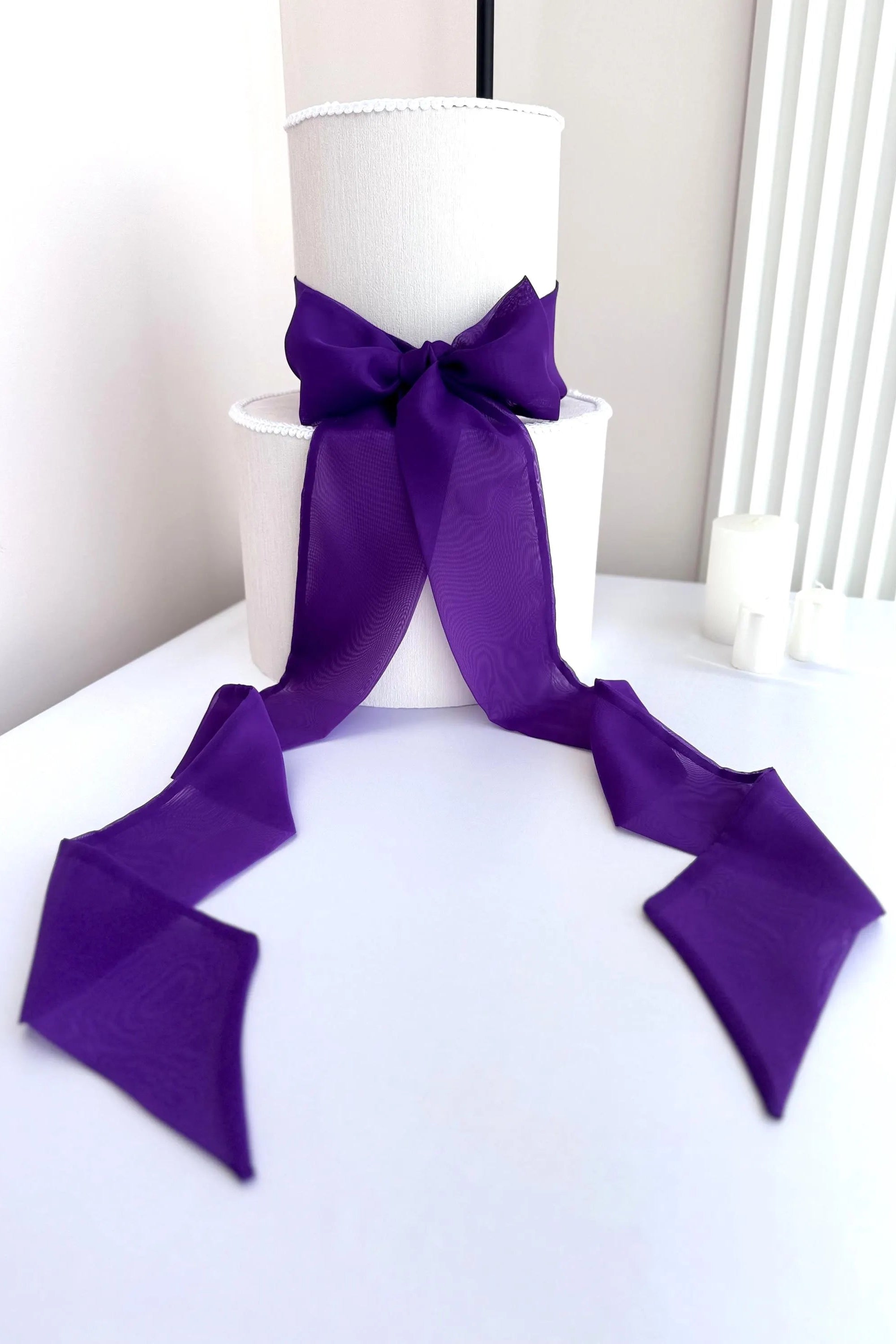 White cake with a purple ribbon on a white surface