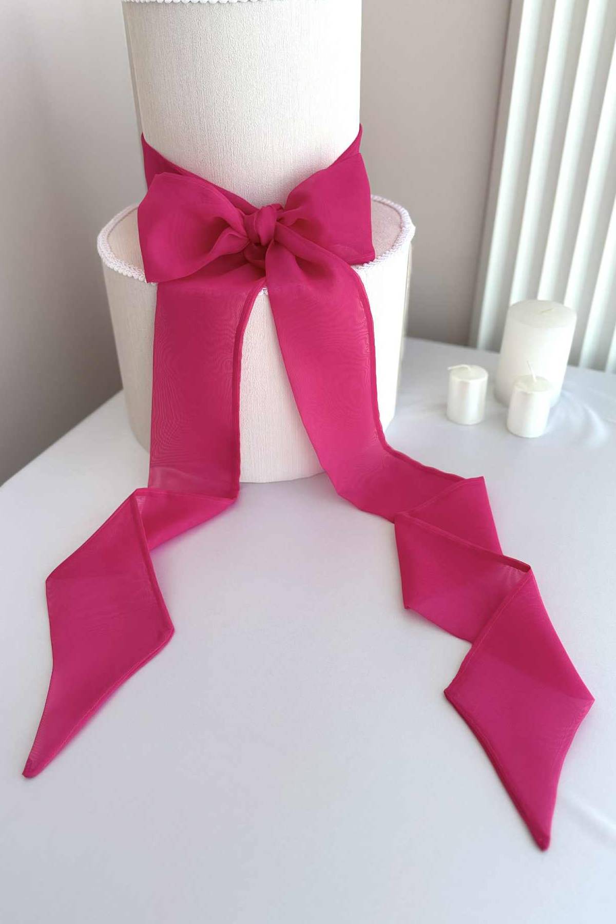 White cake with a large pink bow on a white surface