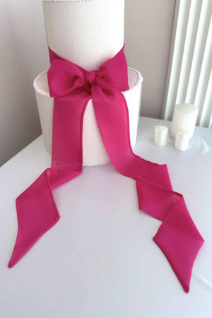 White cake with a large pink bow on a white surface