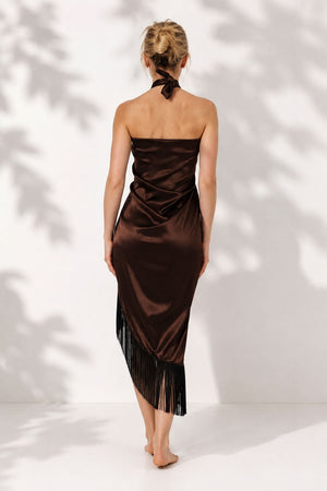 Woman wearing a brown strapless dress with fringe details against a white background