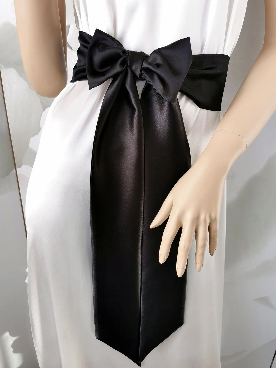 Black satin sash belt tied in a long elegant bow around the waist