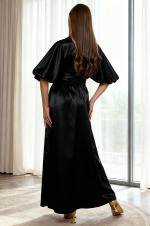Woman wearing a black satin robe in a bright room with large windows