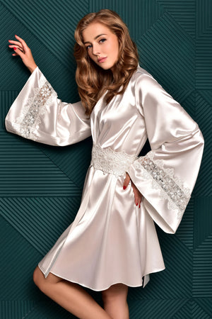 Woman wearing a white satin robe with embellishments against a dark green textured background