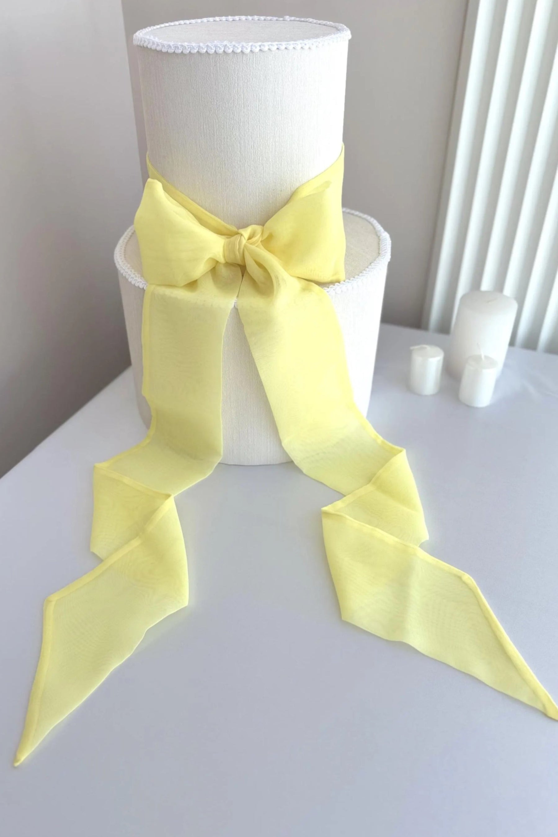 White lampshade with a large yellow bow on a white surface.