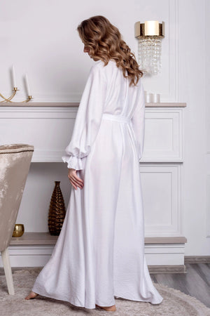 Woman in a white robe standing in a stylish room with decor elements.