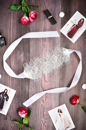 Lace headband on a wooden surface with flowers and fashion magazines.