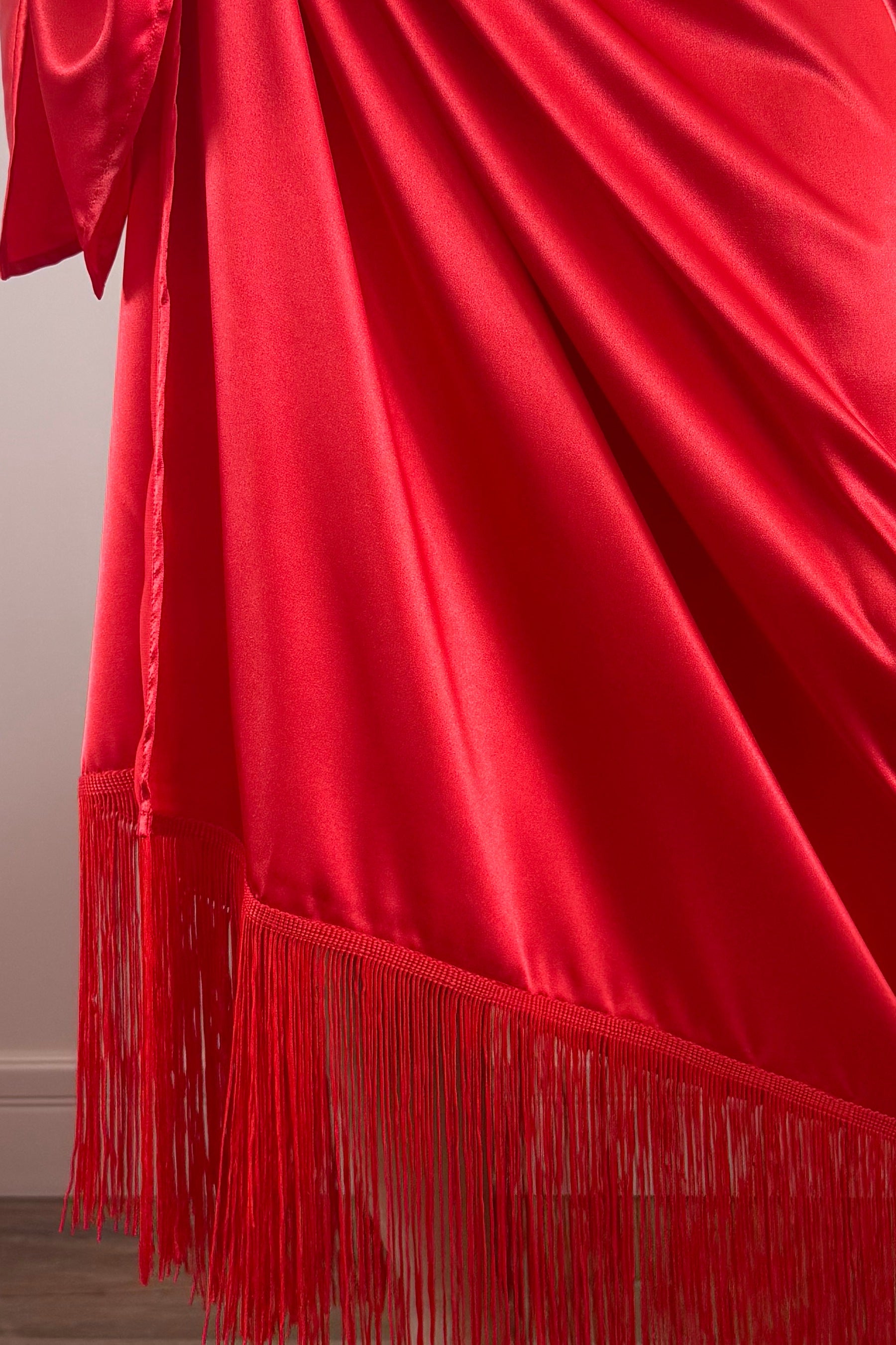 Red fabric with fringes on a plain background