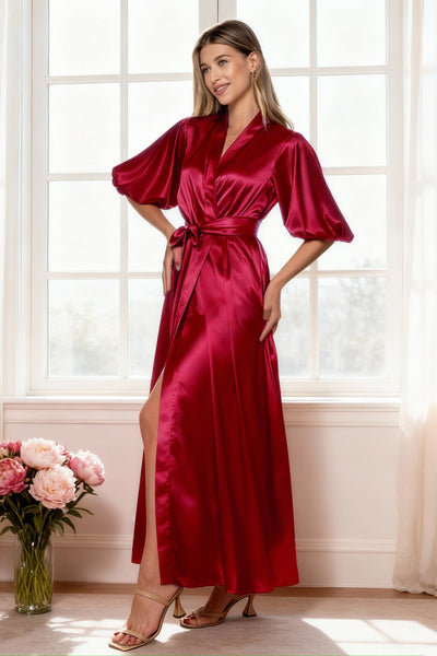Woman wearing a red satin dress standing in a bright room with large windows.
