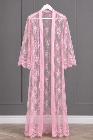 A pink sheer lace robe with floral embroidery and a matching pink satin front panel, hanging on a white hanger against a gray paneled wall.