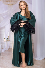 Woman in a green satin dress with black feathered sleeves in an elegant room.