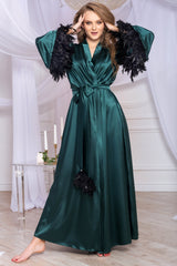 Green satin dress with black feathered sleeves in a decorated room.