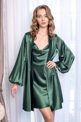 Woman wearing a green satin robe and nightgown against a white curtain background