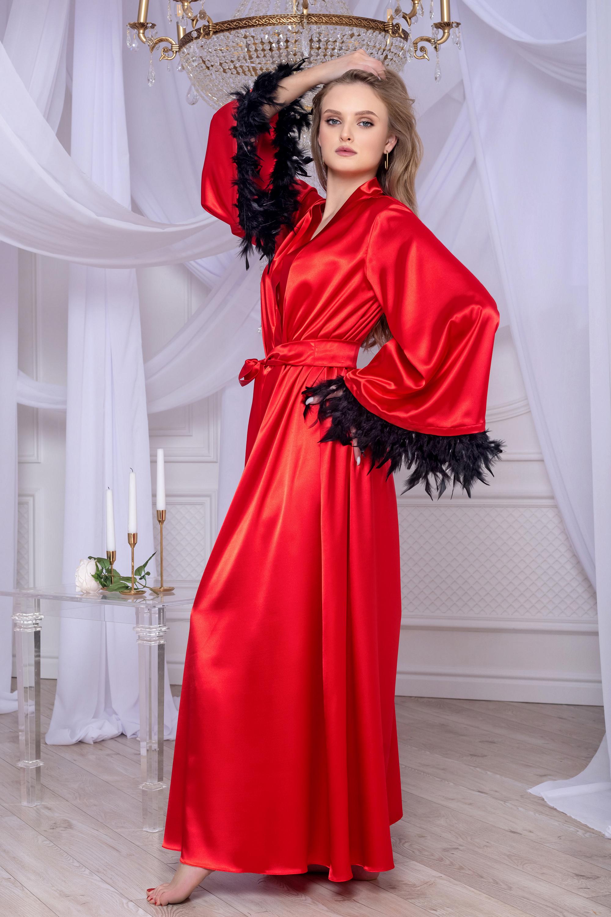 Woman in a red satin robe with black feathered sleeves in a elegant room.