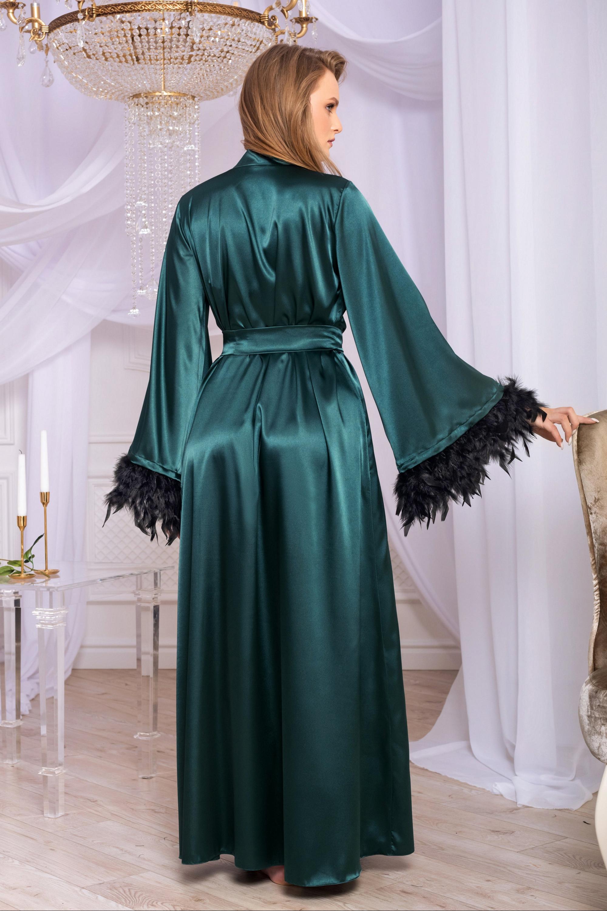 Woman wearing a green satin robe with black feather details in an elegant room.
