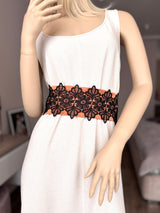 A mannequin wearing a white dress with a black satin waist sash with lace trim.