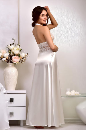 A woman modeling a sleeveless, backless A-line wedding dress with a lace bodice and satin skirt
