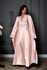 Woman wearing a pink satin robe with lace details against a dark wall.