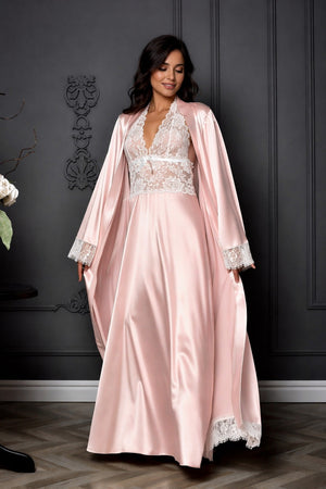 Woman wearing a pink satin robe with lace details against a dark wall.
