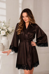 Woman wearing a brown satin robe with lace trim in a softly lit room.