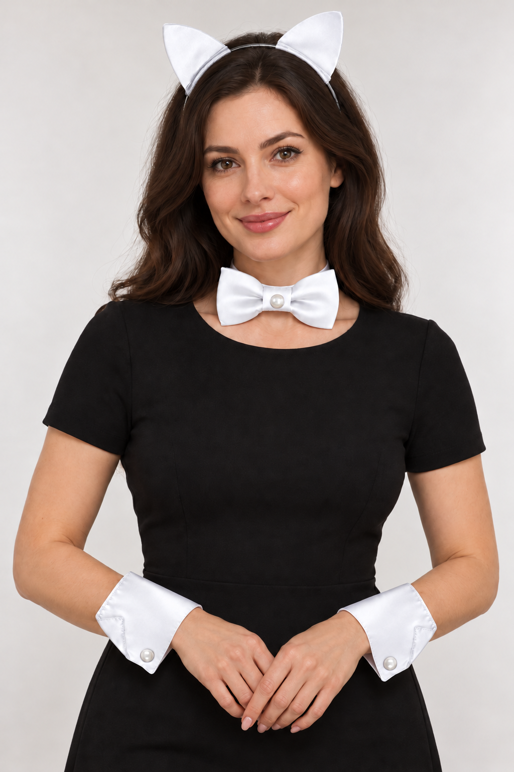 Woman modeling white satin cat ears on a dark metal headband, a matching bow tie and wrist cuffs with a black dress