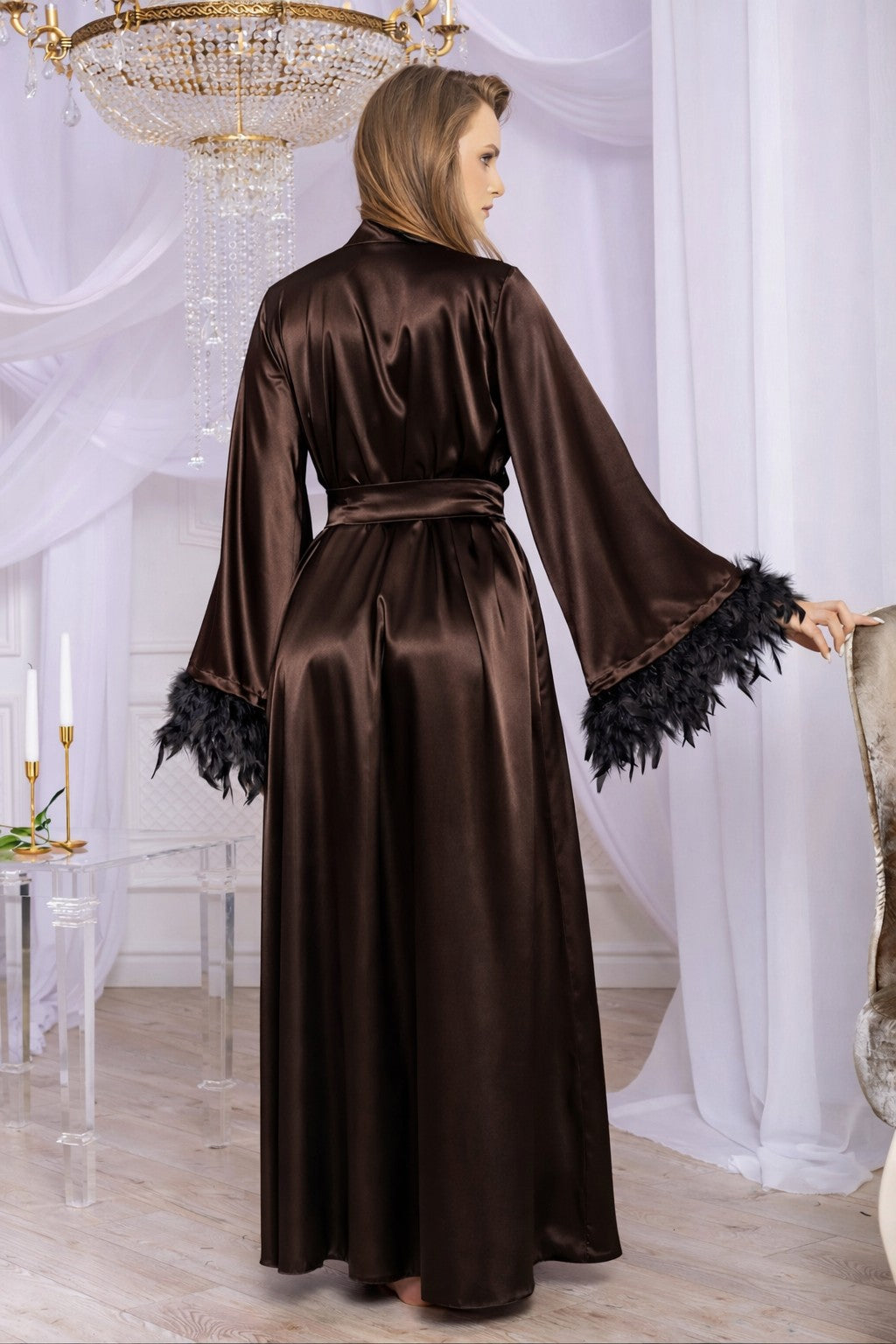 Woman wearing a brown satin robe with black feather trim in a elegant room.