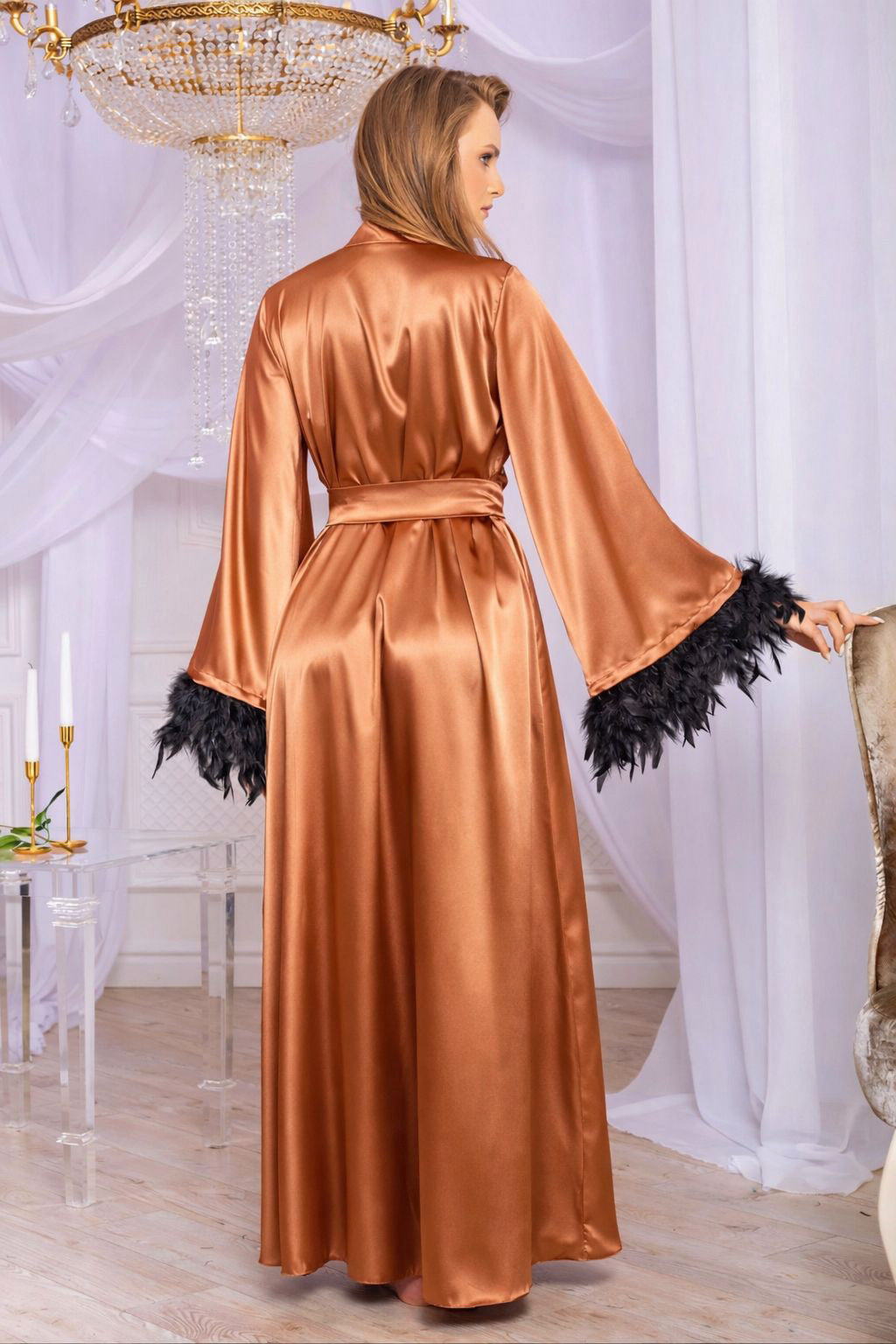 Woman wearing a long, rust satin robe with black fringes in a elegant room.
