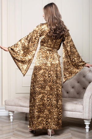 Woman in a leopard print dress standing in a room with a gray sofa.