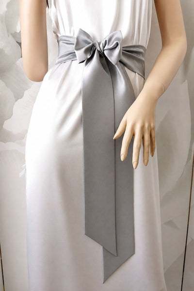 White dress with a large gray bow on a mannequin against a light background