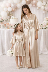 Junior flower girl wearing champagne beige satin robe at wedding