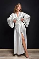 Woman wearing a white satin robe with lace details against a black background