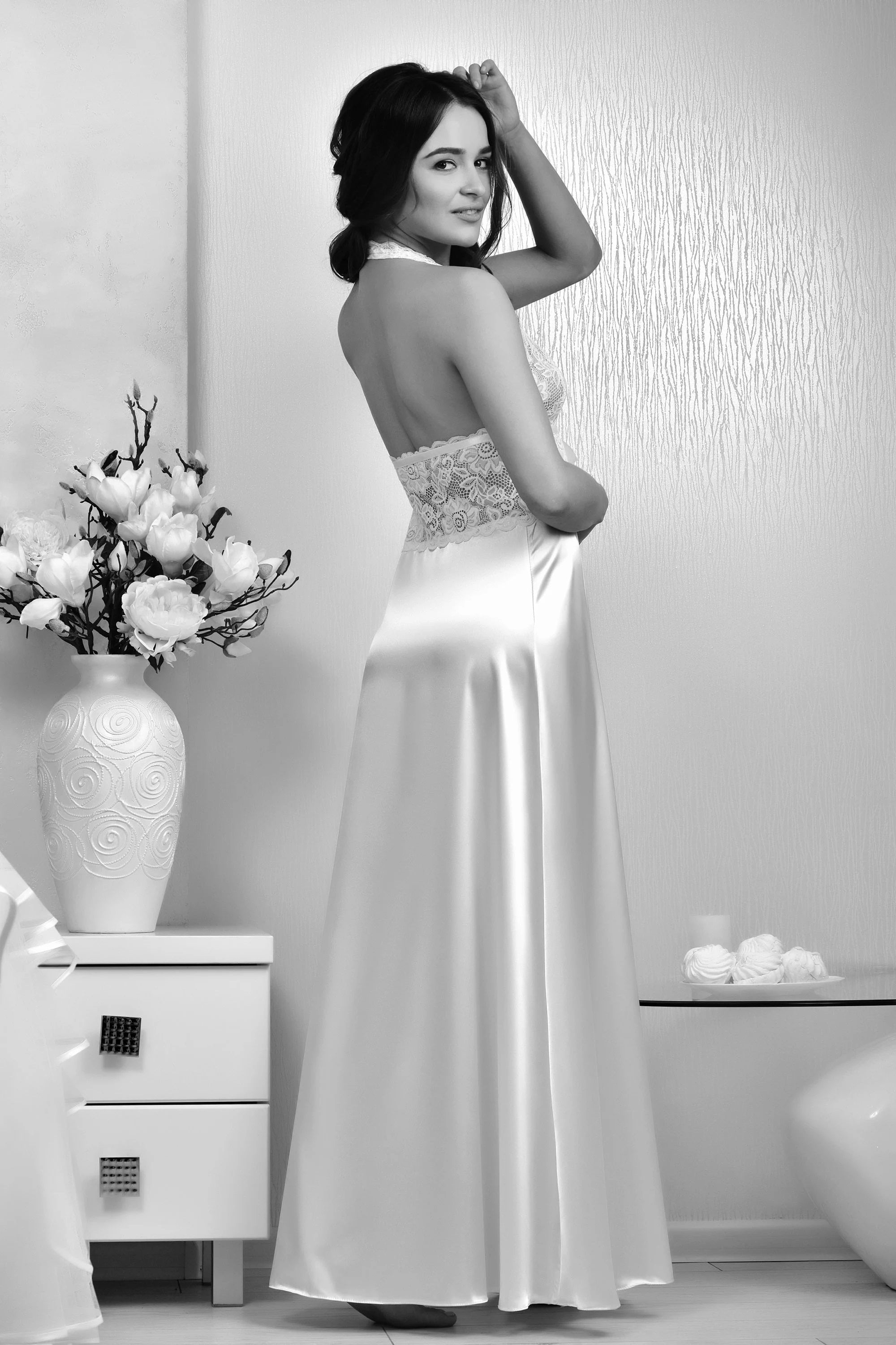 Woman in a evening gown with floral decorations in a minimalistic room.