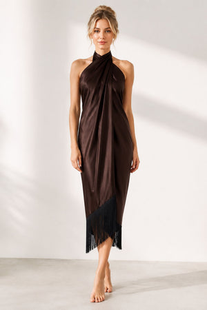 Woman wearing a brown halter neck dress with fringe details on a white background
